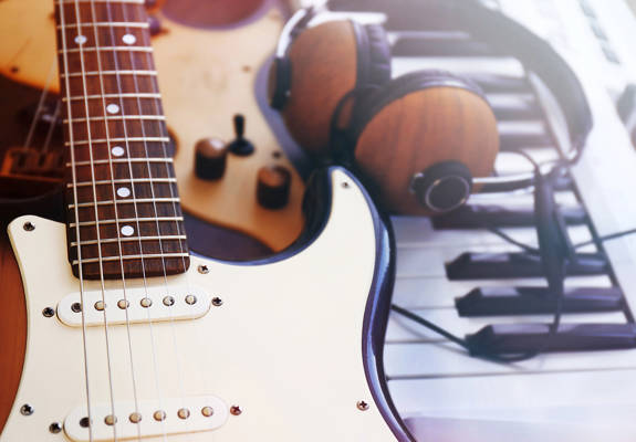 An electric and a classic guitar on top of a piano, next to a pair of headphones